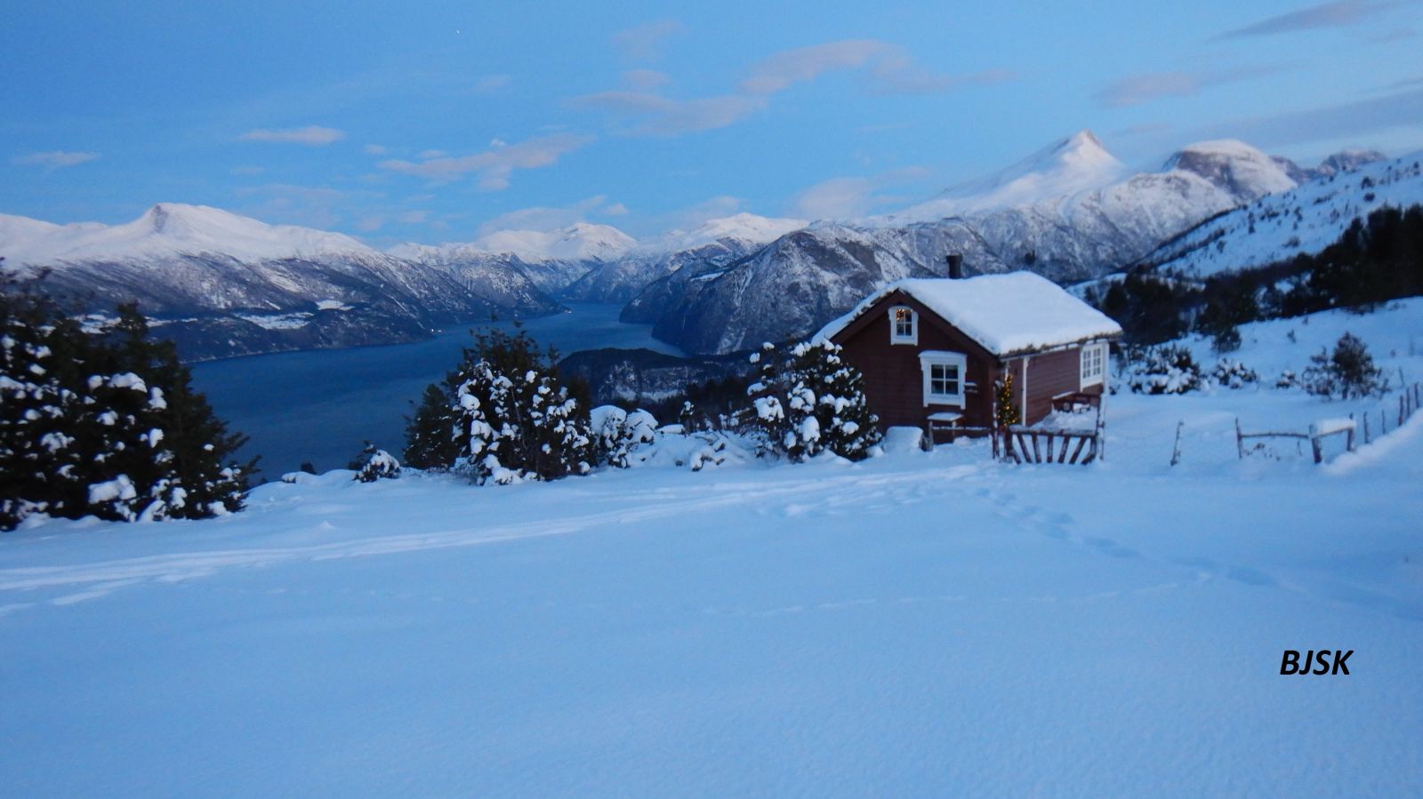 Seterhus i vinterlandskap med utsikt til fjord og fjell